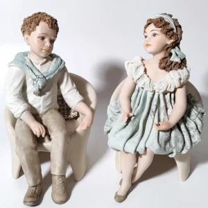 Statuette in porcellana di Alissa e Alan seduti su una poltrona.