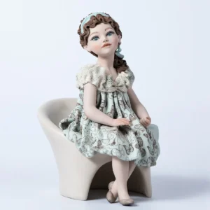 Statua in porcellana di ragazza su poltrona bianca con abito azzurro acquamarina decorato a farfalle e bavero in tulle.