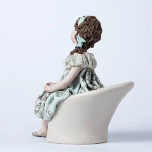 Statua in porcellana di ragazza seduta su poltrona bianca, con abito azzurro acquamarina a farfalle e bavero in tulle.