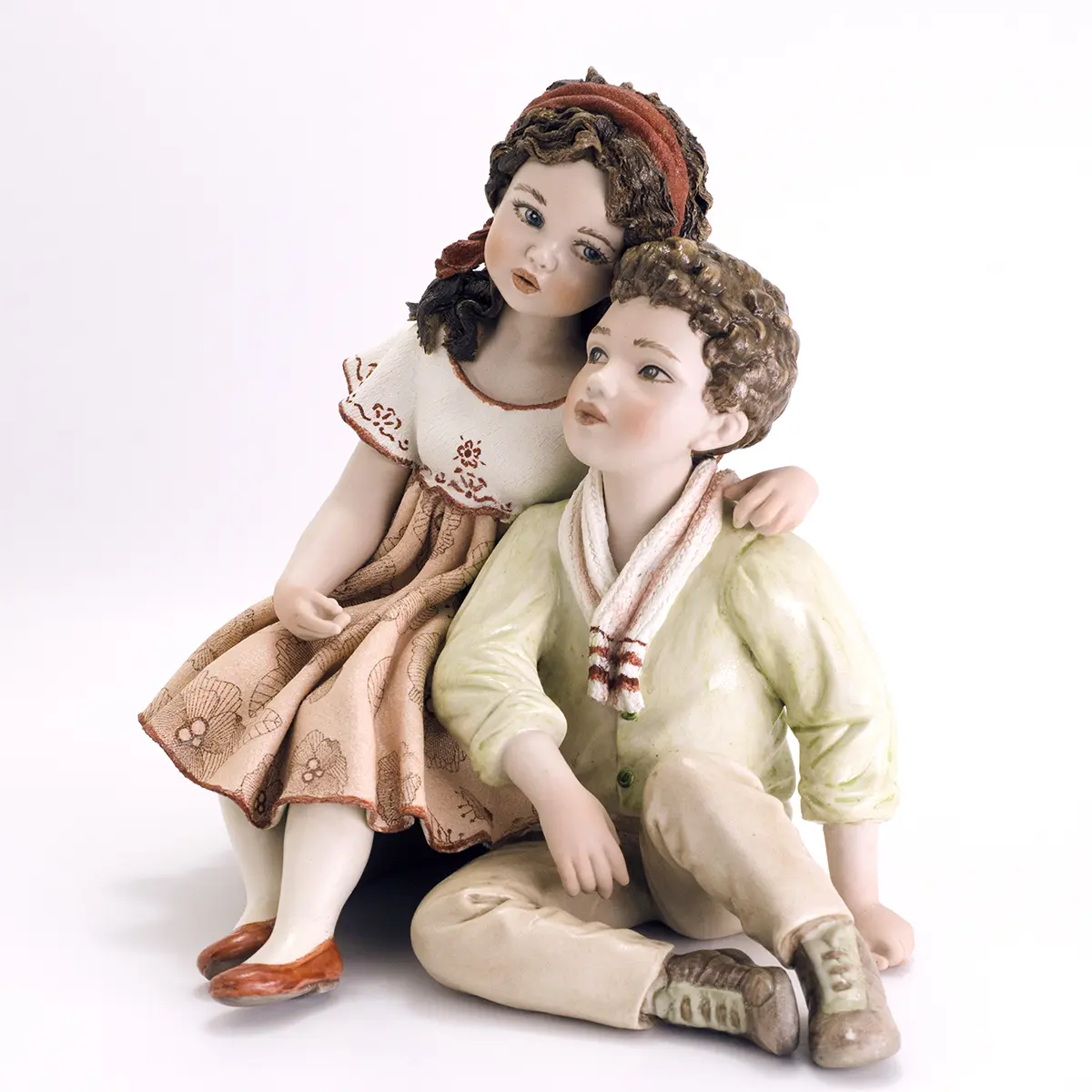 Statua in porcellana di coppia di ragazzi abbracciati, lei in abito rosa a fiori e lui in camicia verde e pantaloni beige.