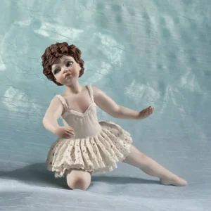 Statua in porcellana di ragazza in tut&ugrave; da ballerina in pizzo, appoggiata su un ginocchio e con fiocco bianco nei capelli.