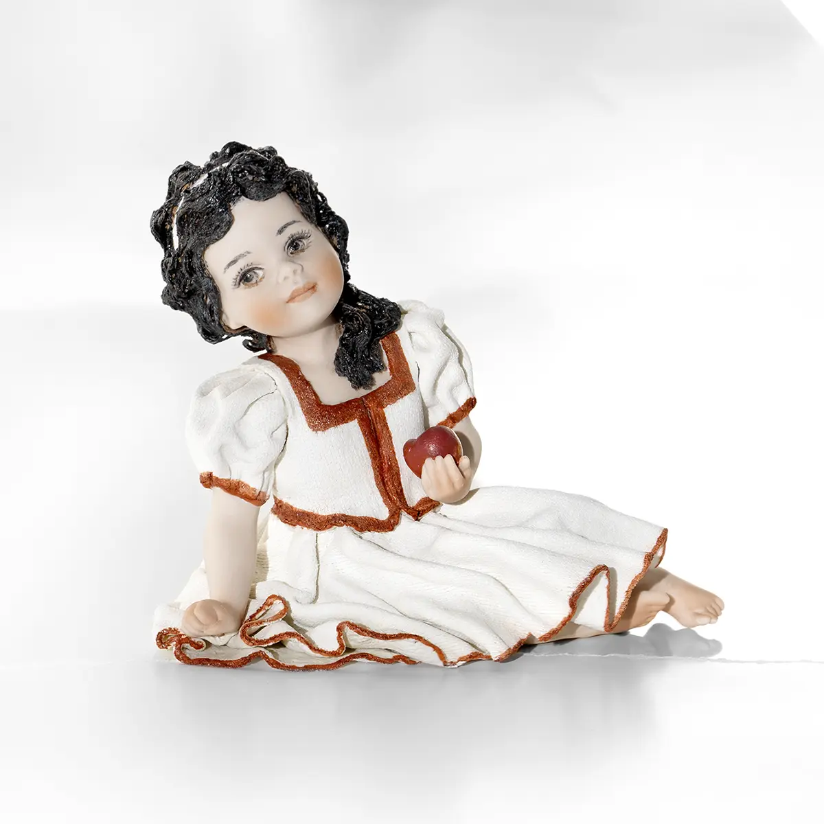 Statua in porcellana di Biancaneve con abito bianco, maniche a palloncino e mela in mano.