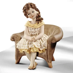 Statua in porcellana di ragazza seduta su poltrona marrone in abito di pizzo con sottogonna e bavero gialli.