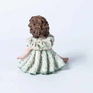 Statua in porcellana di bimba con abito in pizzo bianco e verde, fiocco sul petto e capelli raccolti in due chignon.
