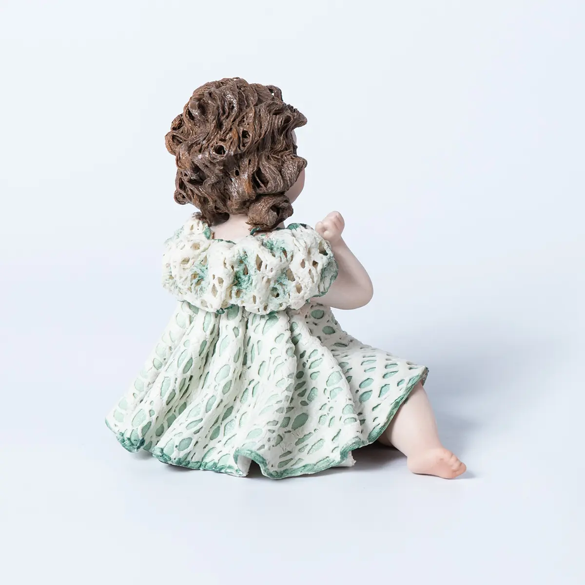 Statua in porcellana di bimba in abito di pizzo bianco e verde, con bavero a sbuffo, fiocco sul petto e due chignon.