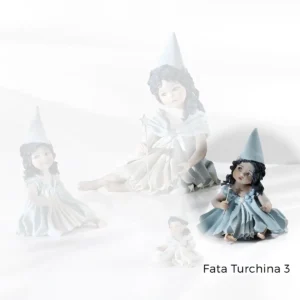Fata turchina in porcellana seduta a terra con capelli sciolti e bacchetta magica argentata con stellina sulla punta.