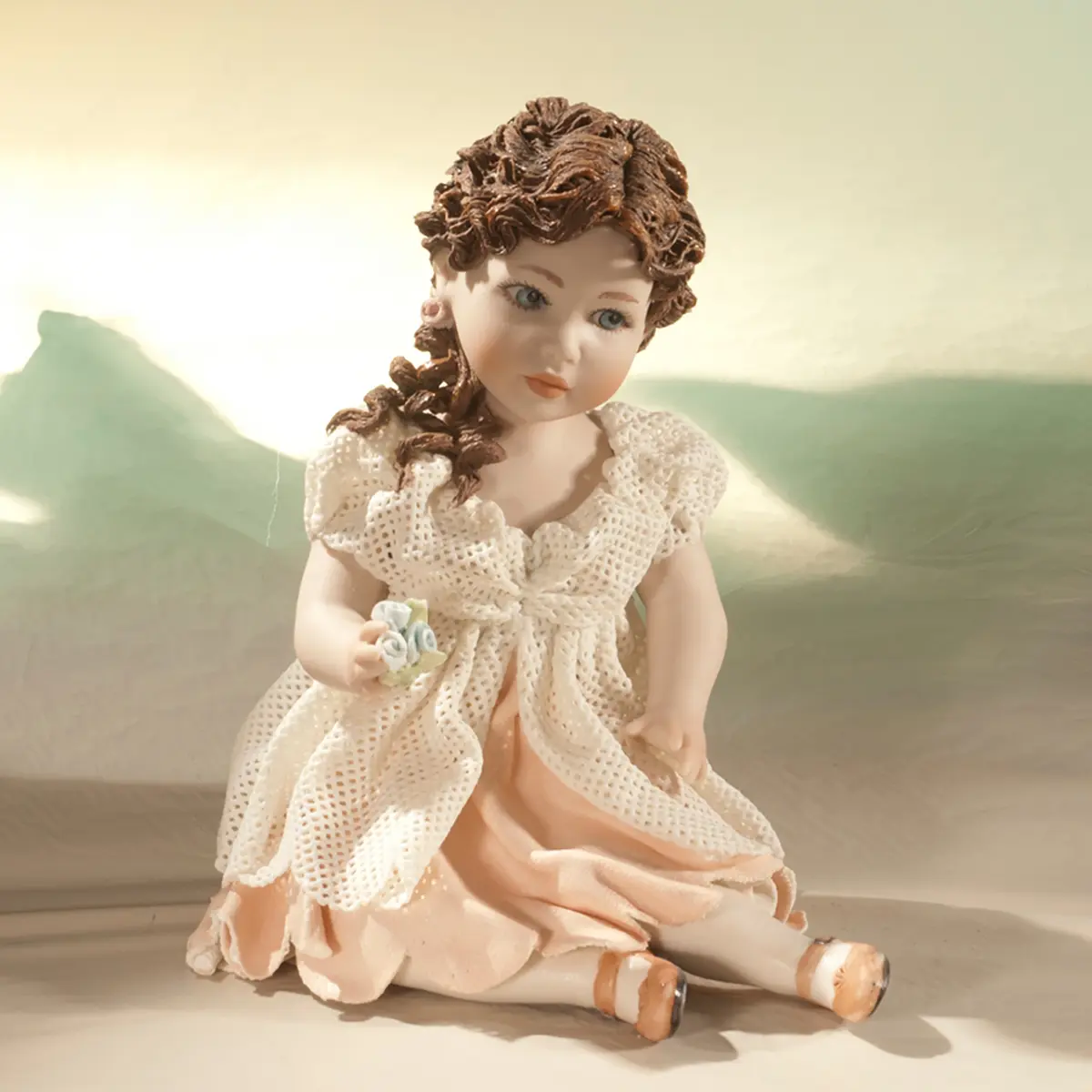 Statua in porcellana di ragazza seduta con abito in tulle, sottogonna rosa e fiorellini in mano.