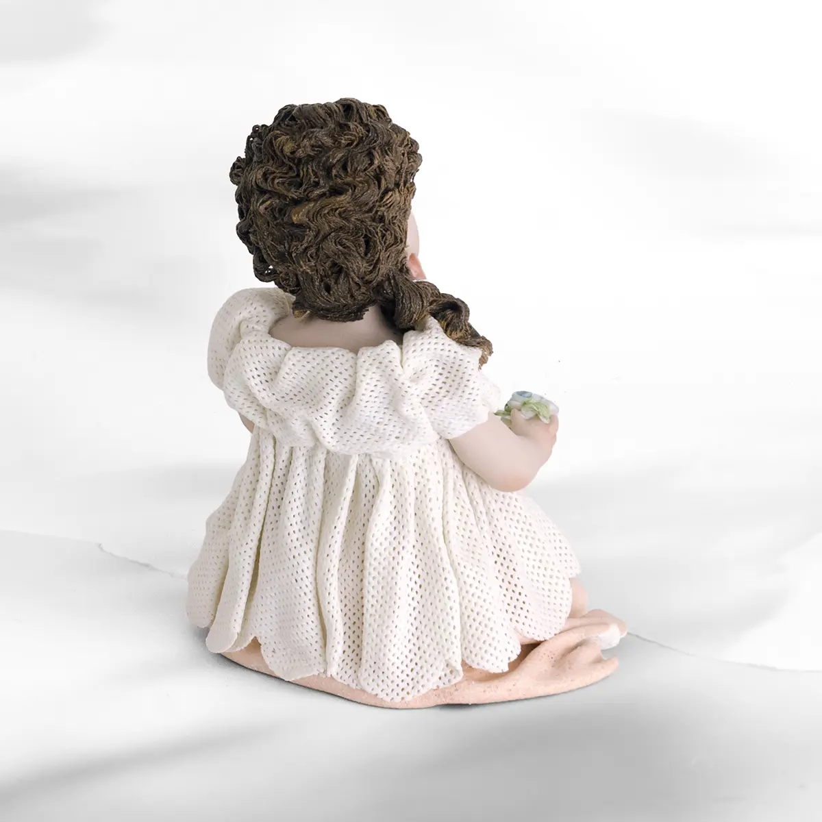 Statua in porcellana di ragazza seduta con abito in tulle, sottogonna rosa e fiorellini colorati in mano.