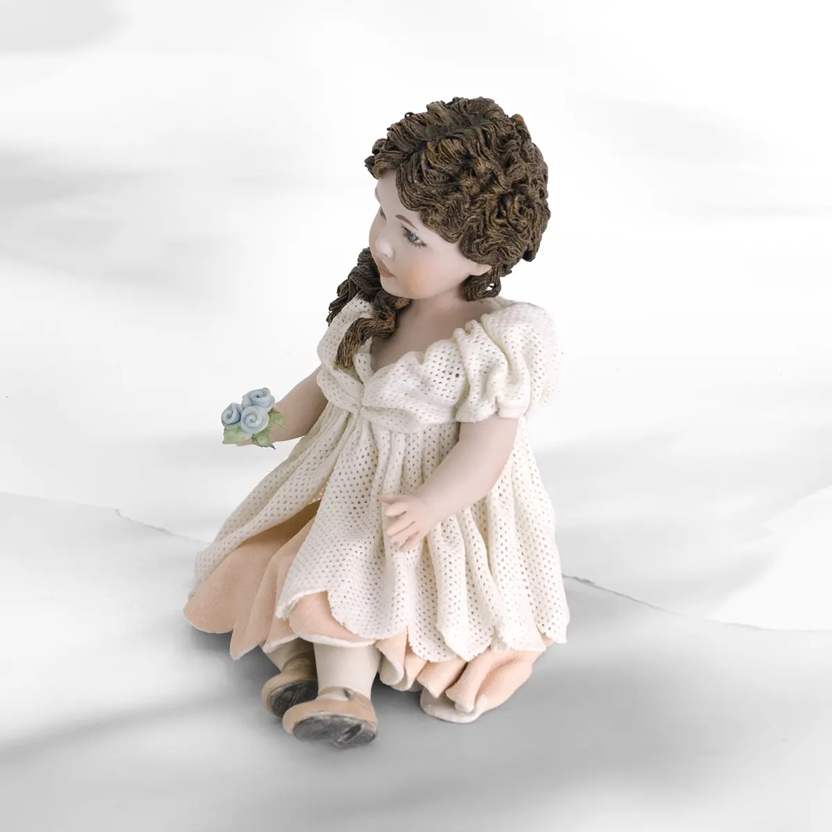 Statua in porcellana di ragazza seduta con abito in tulle, sottogonna rosa e fiorellini colorati in mano.