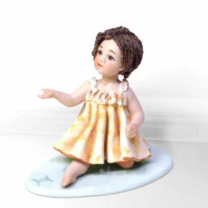 Statua in porcellana mini Gemelli di Sibania con abito giallo in trina e fiore blu tra i capelli.