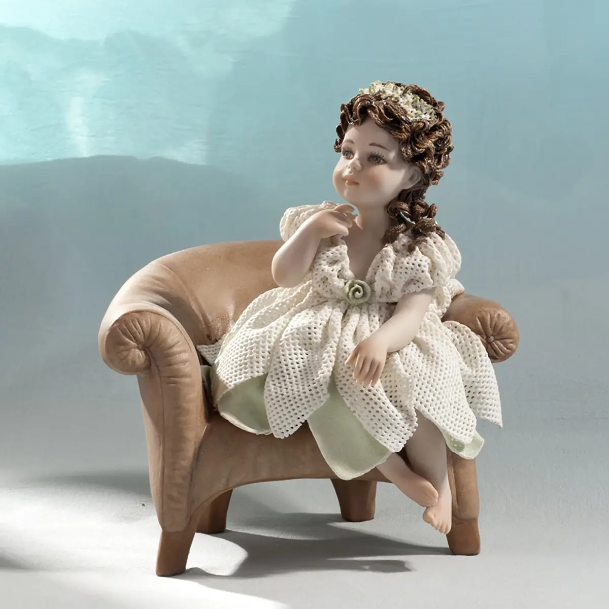 Statua in porcellana di Giulietta seduta in poltrona con abito in tulle verde acqua e rosellina.