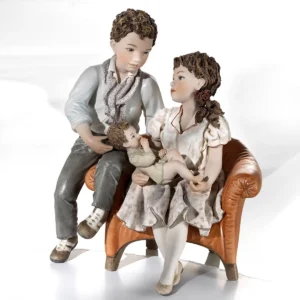 Statua in porcellana raffigurante una famiglia riunita attorno al bimbo piccolo, con madre in rosa e padre in azzurro.