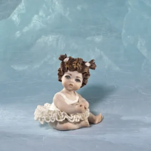 Statua in porcellana di bimba ballerina in tut&ugrave; di pizzo, seduta a terra con due codine corte e fiocchetti bianchi.