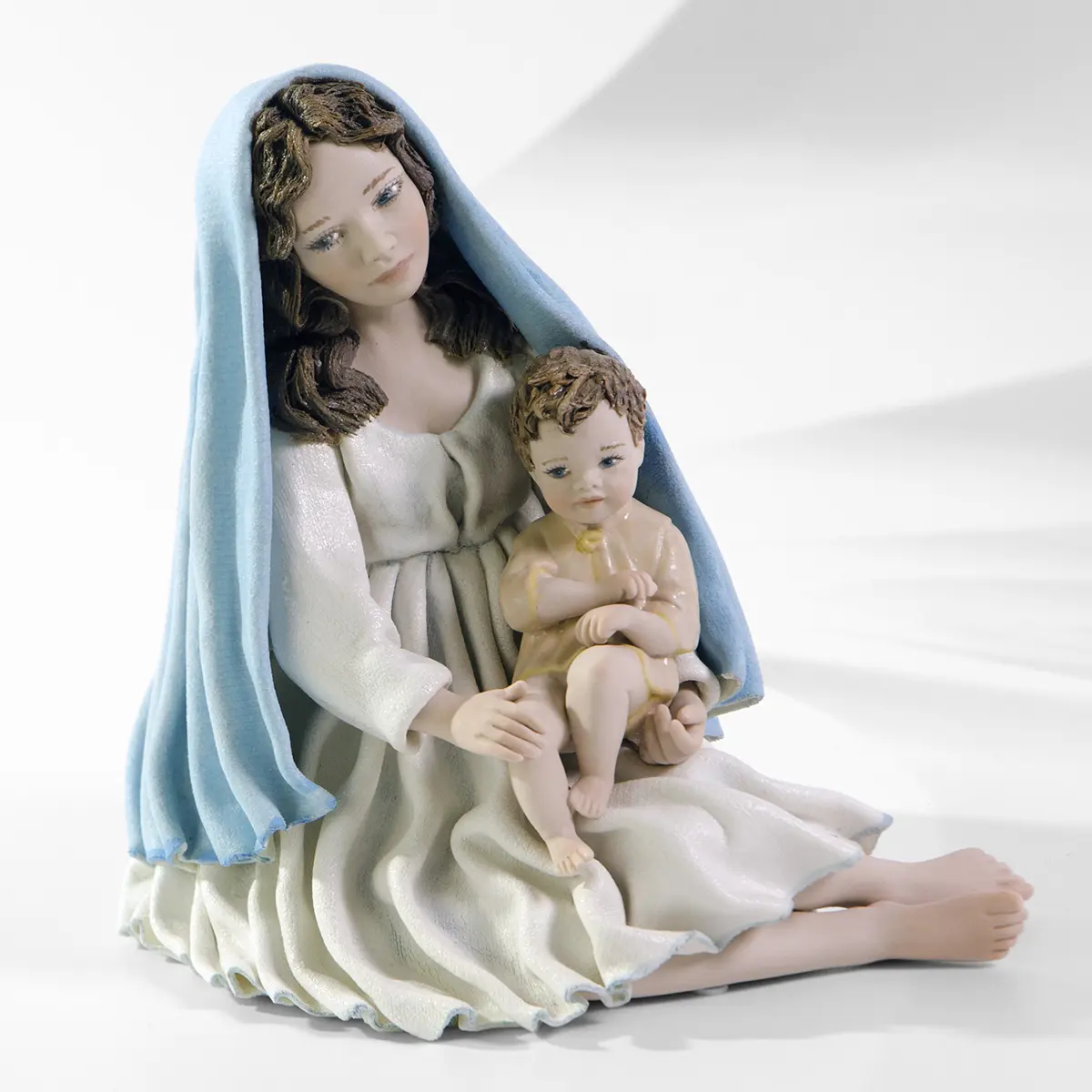 Statua in porcellana della Madonna con Gesù Bambino, abito bianco, velo azzurro e Gesù con casacchina color crema.