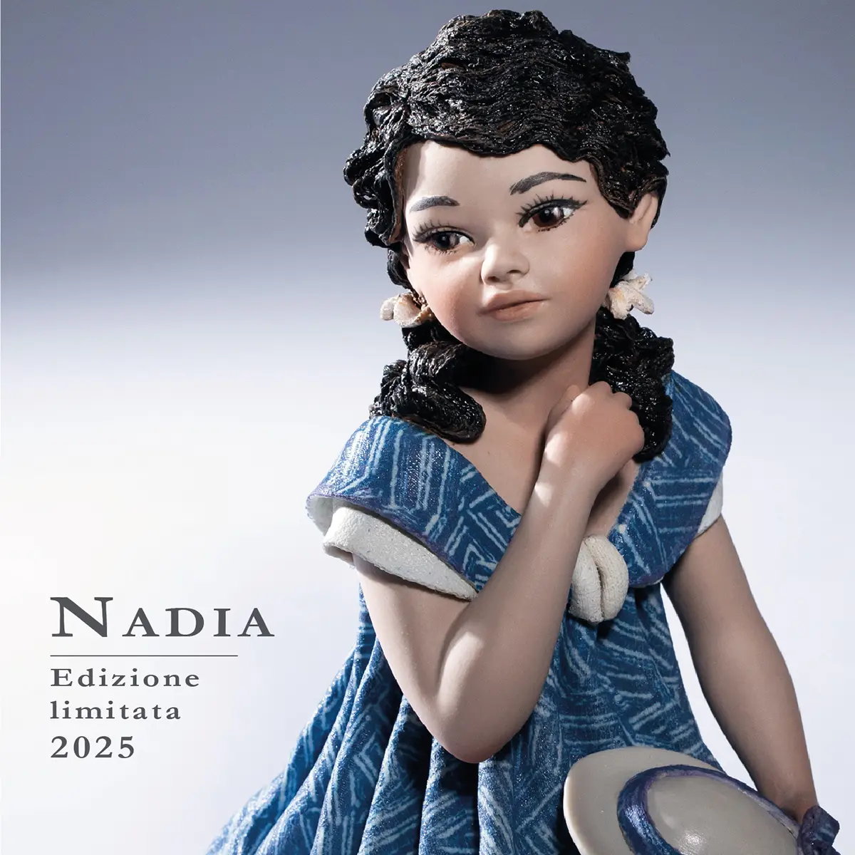 Statua in porcellana Nadia di Sibania in abito indaco, seduta su pouf malva con cappellino bianco in grembo.