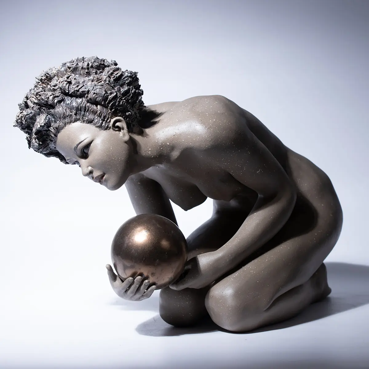 Statua in gres e metallo raffigurante una donna china che regge un globo sulla mano.