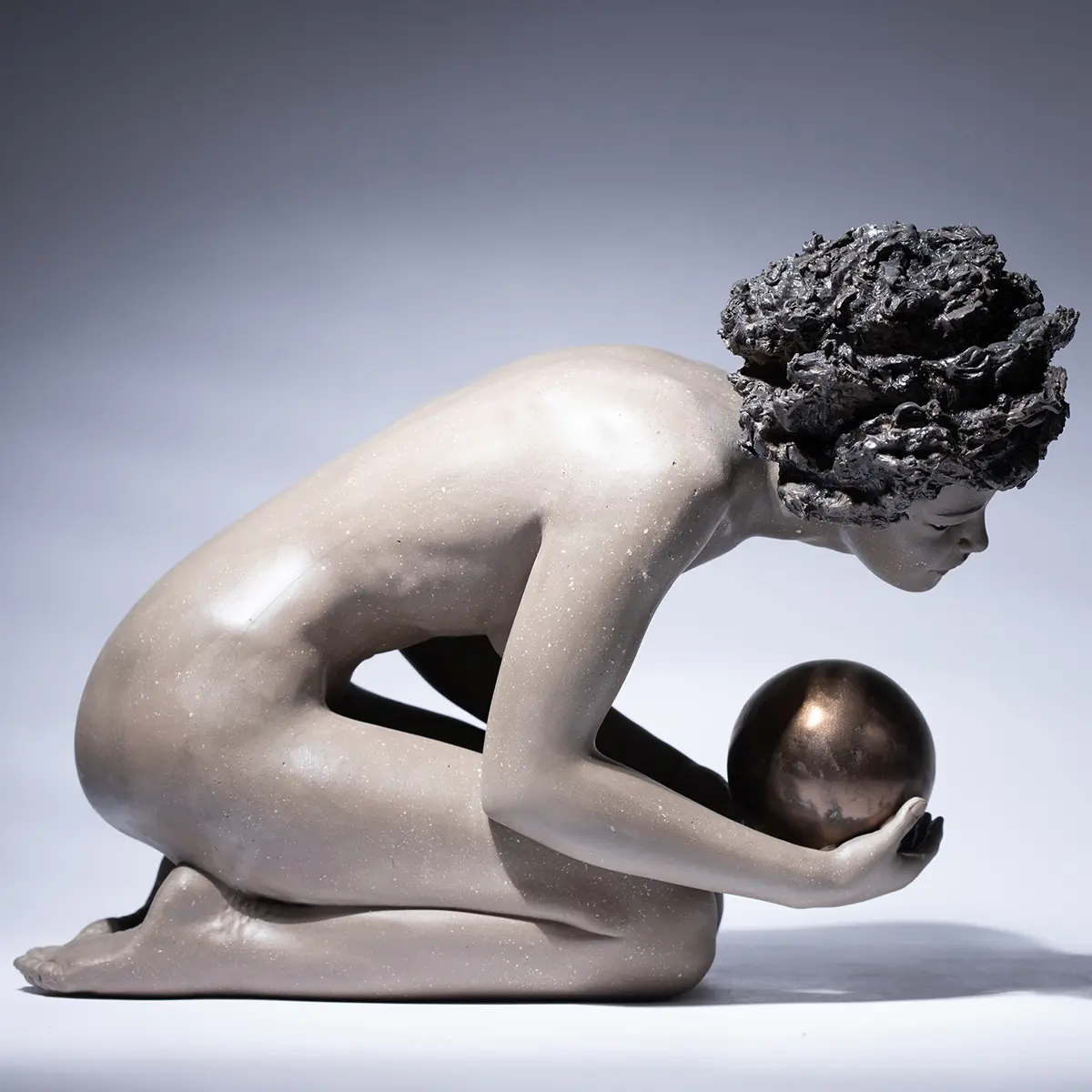 Scultura in gres e metallo raffigurante una donna china che regge un globo sulla mano.