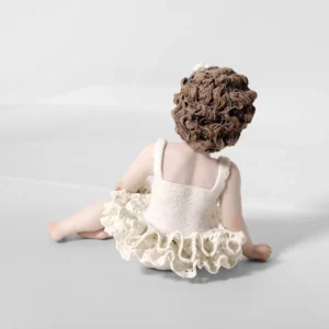 Statua in porcellana di bimba ballerina in tut&ugrave; di pizzo, seduta a terra con fiocco bianco nei capelli.