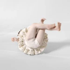 Statua in porcellana di bimba ballerina in tut&ugrave; di pizzo, seduta a terra con fiocco bianco di lato nei capelli.