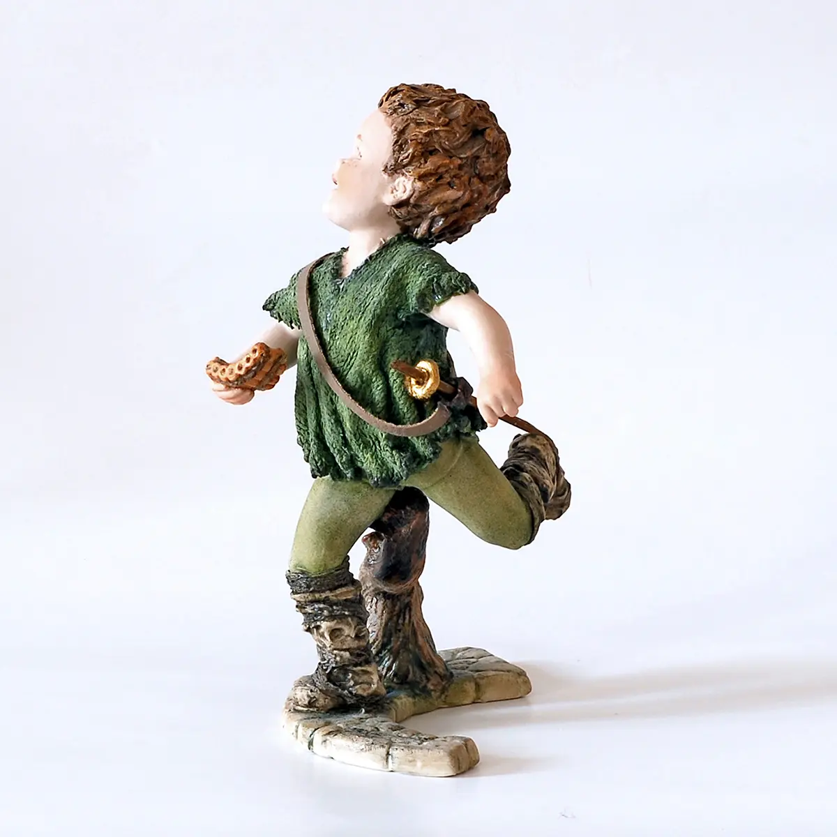 Statua in porcellana di Peter Pan con casacca verde bosco, flauto di bambù e spadino al fianco.