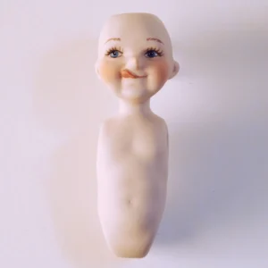 Bambolina in porcellana biscuit raffigurante un piccolo Pinocchio con la linguetta di fuori e il naso lungo.