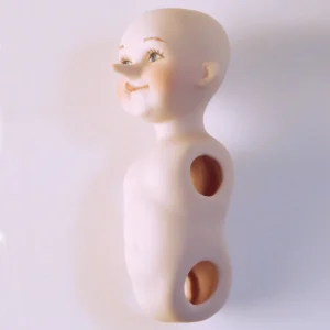 Bambolina in porcellana biscuit di Pinocchio con la linguetta di fuori e il naso lungo.