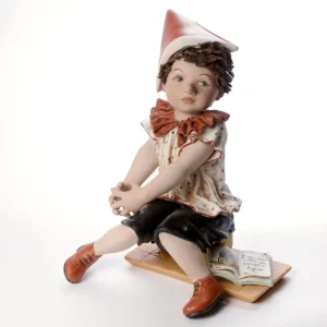 Statue in porcellana raffiguranti Pinocchio in casacca a pois rossi e cappello rosso, in quattro diverse dimensioni.