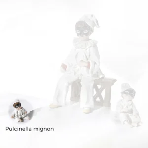 Statua in porcellana di Pulcinella mignon seduto a terra, con abito bianco, berretto a punta e maschera nera.