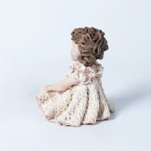 Statua in porcellana di bimba in abito di pizzo bianco e rosa con fiocco sul petto e chignon laterale.