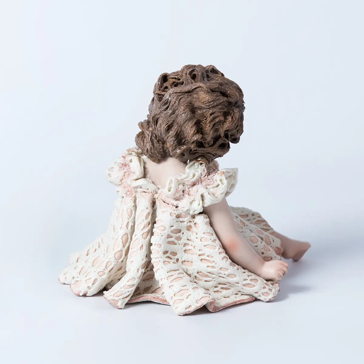 Statua in porcellana di bimba in abito di pizzo bianco e rosa con fiocco sul petto e chignon laterale.