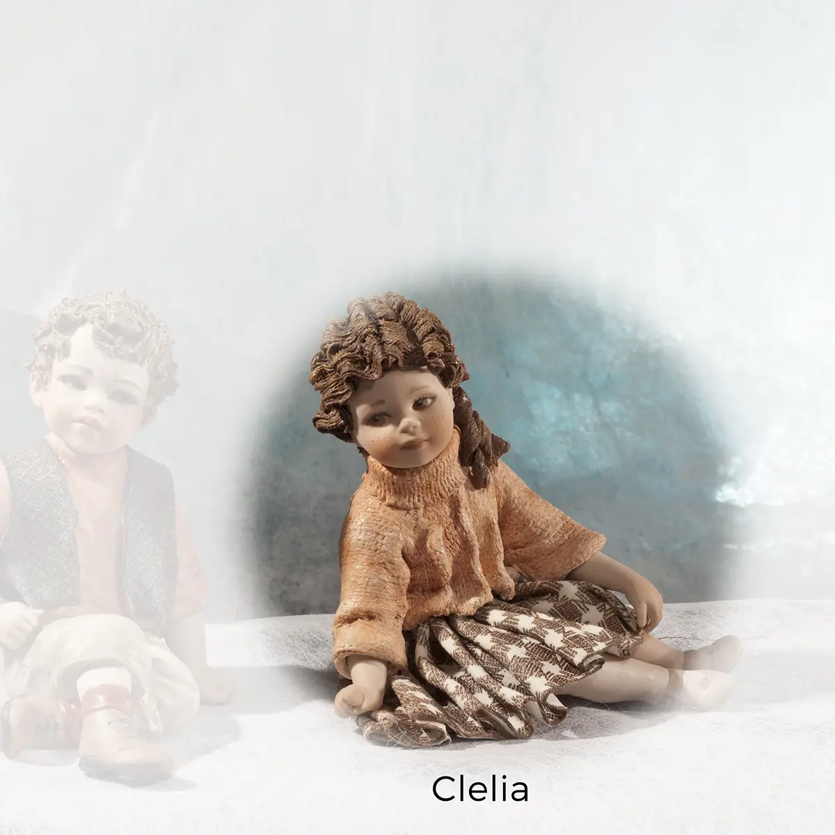 Statua in porcellana Clelia: ragazza seduta a terra con maglioncino salmone e gonna bianca e bruna.