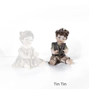 Statua in porcellana di Tin Tin: bimbo seduto a terra in maglia verde, gilet bruno, pantaloni a quadri e berretto.